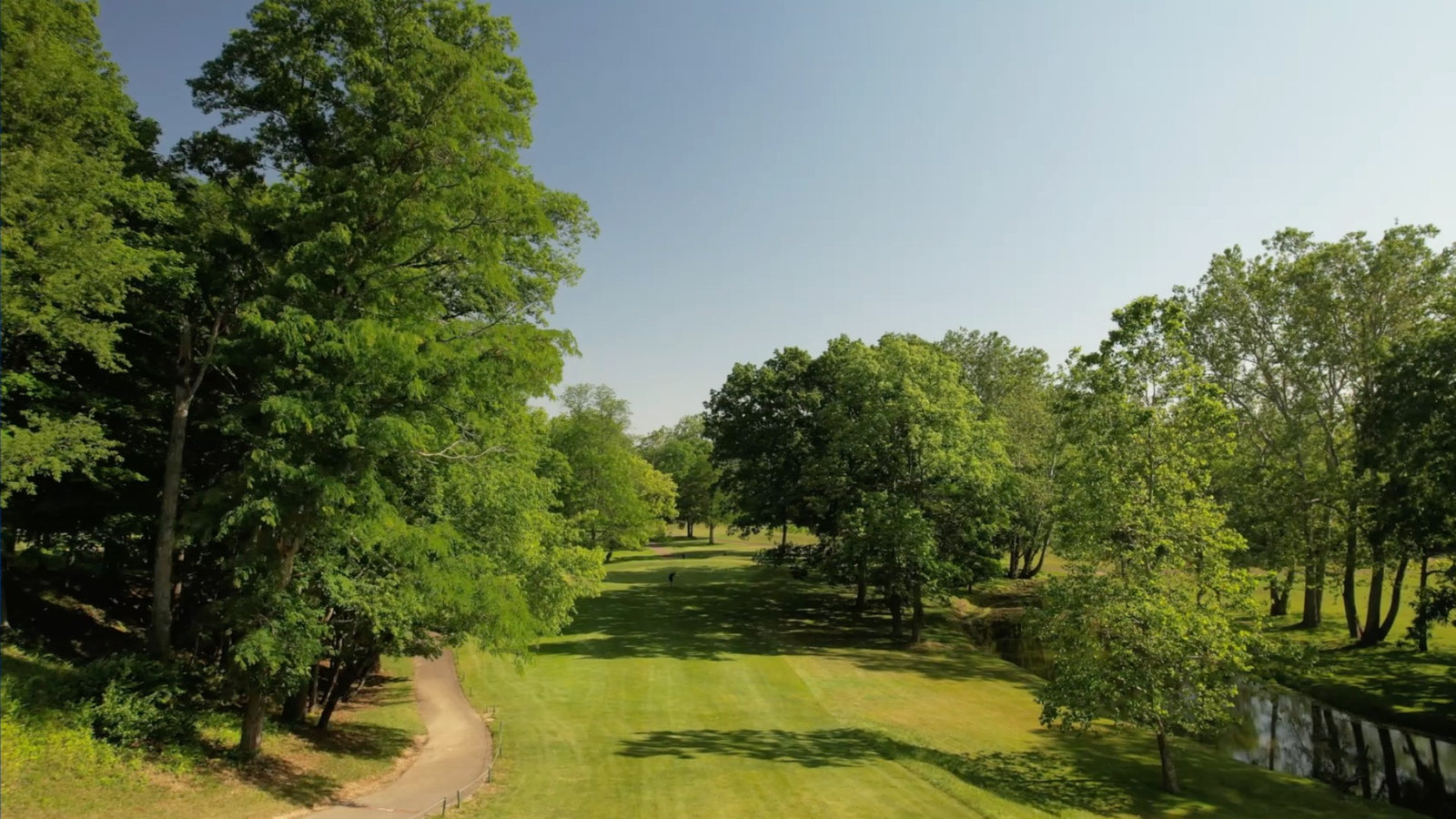 Aerial drone view of a tree-lined golf course fairway